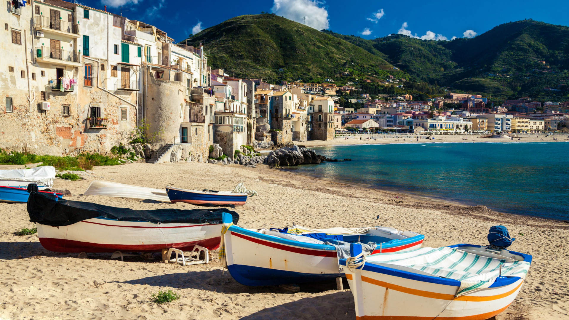 Sicilië - strand met vissersbootjes- stadje in achtergrond