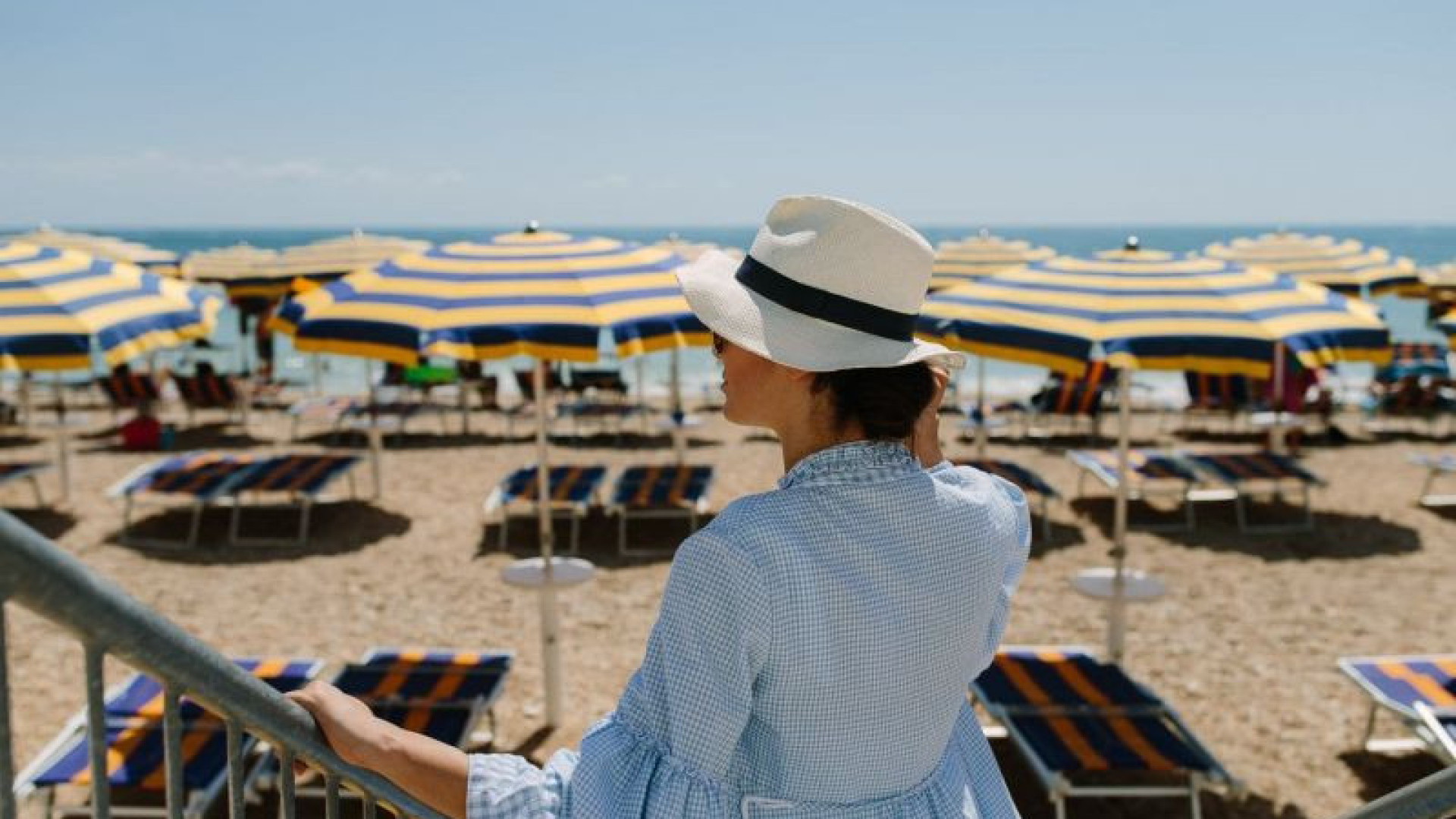 Strand vrouw met hoed bedjes en parasols le Marche Numana aan de oostkust van Italië